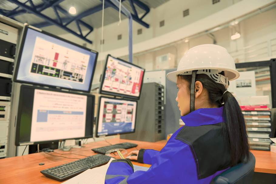 Image of a woman working on a computer with industrial dashboards on the screen in industrial environment